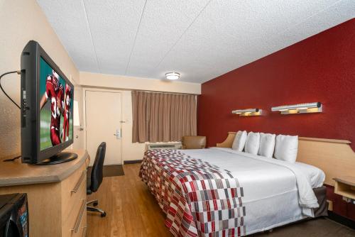 a hotel room with a bed and a flat screen tv at Red Roof Inn Mystic - New London in New London
