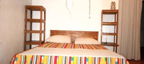a bedroom with a bed with two wooden shelves at Campement Sindéye in Abémé
