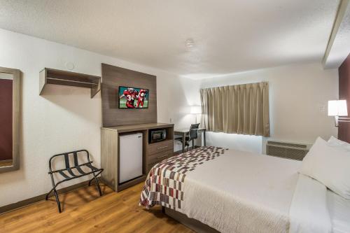 a hotel room with a bed and a chair at Red Roof Inn Rochester - Airport in Rochester