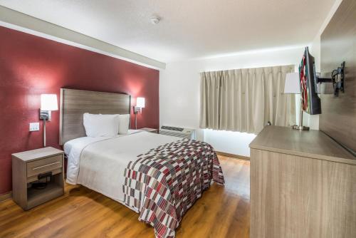 a bedroom with a large bed and a red wall at Red Roof Inn Rochester - Airport in Rochester