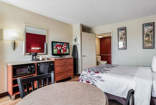 a hotel room with a bed and a flat screen tv at Red Roof Inn Gallup in Gallup