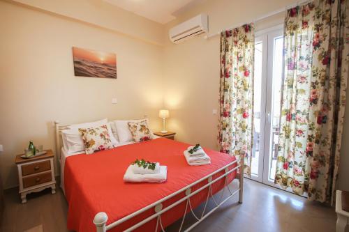 a bedroom with a red bed and a window at Navigator Villas - Houses in Acharavi