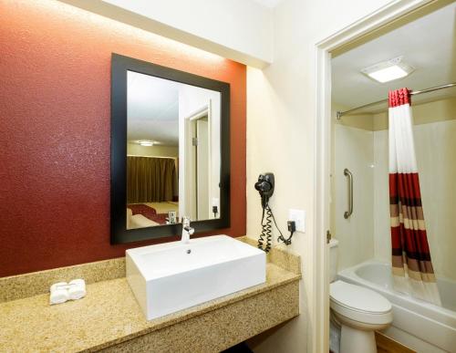 ein Badezimmer mit einem Waschbecken, einem WC und einem Spiegel in der Unterkunft Red Roof Inn Columbus West - Hilliard in New Rome