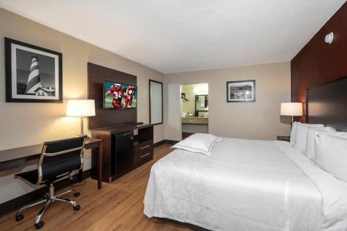 a hotel room with a bed and a desk and a chair at Red Roof Inn PLUS+ St. Augustine in Saint Augustine