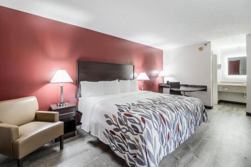 a hotel room with a bed and a chair at Red Roof Inn Cadiz in Cadiz