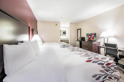 Habitación de hotel con cama grande y escritorio. en Red Roof Inn Cadiz en Cadiz