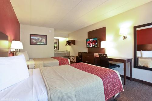 a hotel room with two beds and a desk at Red Roof Inn Michigan City in Michigan City