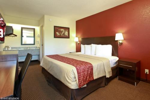 a hotel room with a bed with a red wall at Red Roof Inn Michigan City in Michigan City