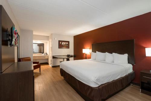ein Hotelzimmer mit einem großen Bett und einem Schreibtisch in der Unterkunft Red Roof Inn Mobile North – Saraland in Saraland