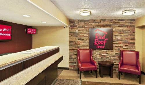 a restaurant with two red chairs and a bar at Red Roof Inn Detroit - Farmington Hills in Farmington Hills