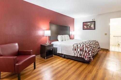 a hotel room with a bed and a chair at Red Roof Inn Forsyth in Forsyth