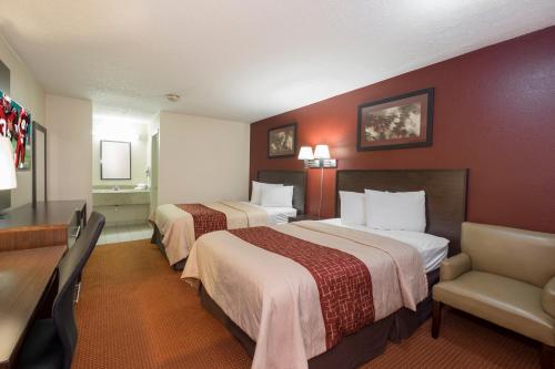 a hotel room with two beds and a chair at Red Roof Inn Columbus Northeast Westerville in Westerville