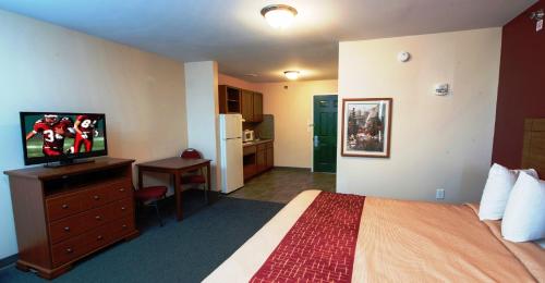 a hotel room with a bed and a flat screen tv at Red Roof Inn & Suites Dickinson in Dickinson