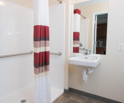 a bathroom with a red and white shower curtain and a sink at Red Roof Inn & Suites Dickinson in Dickinson