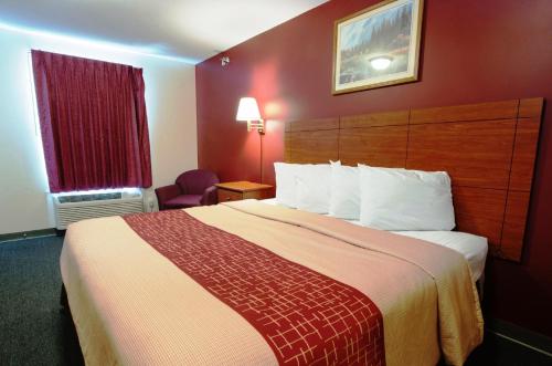 a hotel room with a large bed and a red wall at Red Roof Inn & Suites Dickinson in Dickinson