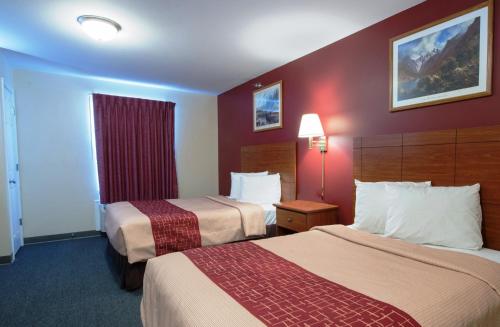 a hotel room with two beds and a red wall at Red Roof Inn & Suites Dickinson in Dickinson