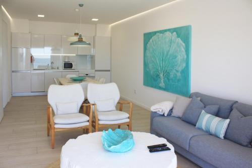 ein Wohnzimmer mit einem blauen Sofa und weißen Stühlen in der Unterkunft Front Sea Apartment in Quarteira