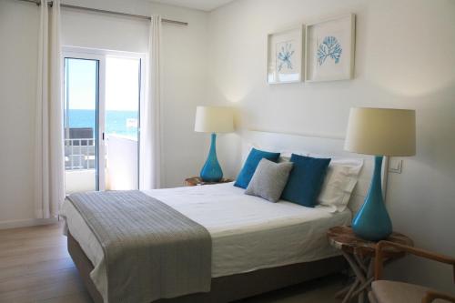 een slaapkamer met een bed met blauwe lampen en een balkon bij Front Sea Apartment in Quarteira