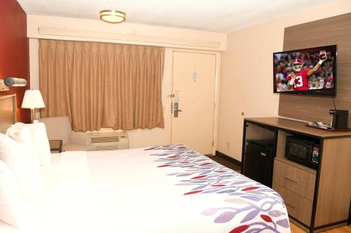 a hotel room with a bed and a flat screen tv at Red Roof Inn Richmond South in Richmond