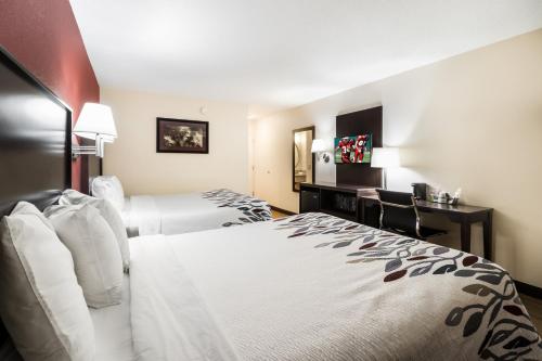ein Hotelzimmer mit 2 Betten und einem Schreibtisch in der Unterkunft Red Roof Inn Murfreesboro in Murfreesboro