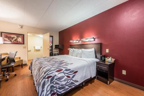 a hotel room with a bed and a red wall at Red Roof Inn Merrillville in Merrillville