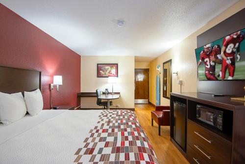 ein Hotelzimmer mit einem Bett und einem Flachbild-TV in der Unterkunft Red Roof Inn Cameron in Cameron