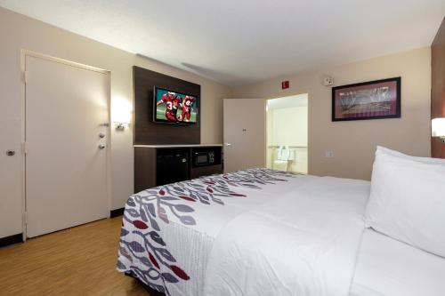 a hotel room with a bed and a television on the wall at Red Roof Inn Gadsden in Gadsden