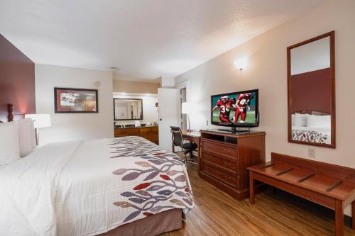 a hotel room with a bed and a flat screen tv at Red Roof Inn & Suites Calhoun in Calhoun