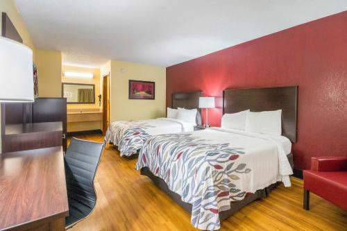 a hotel room with two beds and a red wall at Red Roof Inn Clarksville in Clarksville