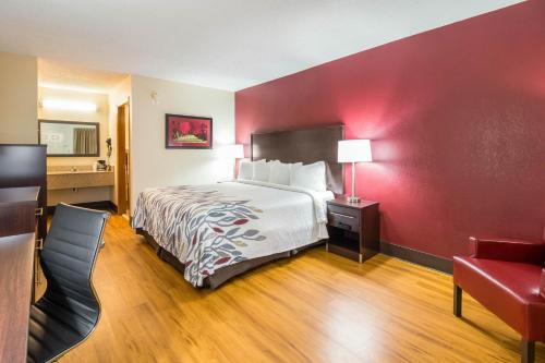 a hotel room with a bed and a red wall at Red Roof Inn Clarksville in Clarksville