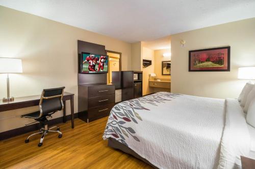 a hotel room with a bed and a desk and a computer at Red Roof Inn Clarksville in Clarksville