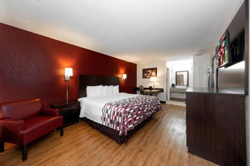 Habitación de hotel con cama y silla roja en Red Roof Inn Ft Pierce en Fort Pierce