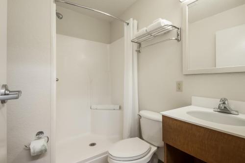 a white toilet sitting next to a sink in a bathroom at HomeTowne Studios by Red Roof Dallas - Mesquite in Mesquite