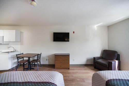 a room with a kitchen and a table with a chair at HomeTowne Studios by Red Roof St. Louis - Airport/N Lindbergh in Hazelwood