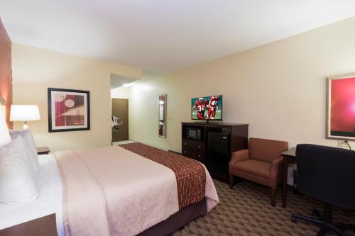 a hotel room with a bed and a chair at Red Roof Inn & Suites Cincinnati North-Mason in Mason