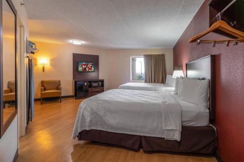 a hotel room with a large bed and a chair at Red Roof Inn PLUS+ El Paso East in El Paso