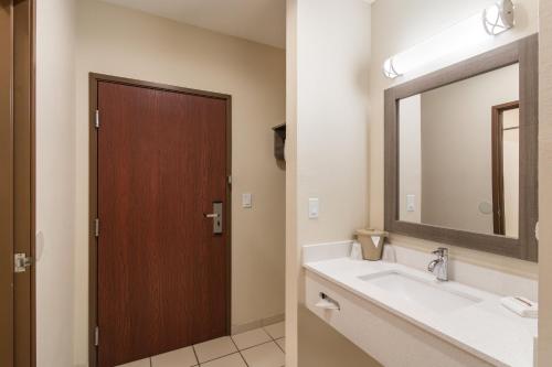 a bathroom with a sink and a mirror and a door at Red Roof Inn Panama City in Panama City