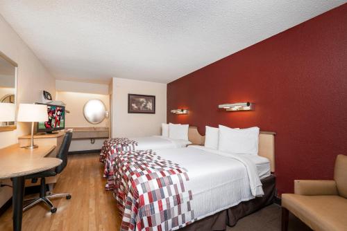 a hotel room with a large bed with a red wall at Red Roof Inn Chesapeake Conference Center in Chesapeake