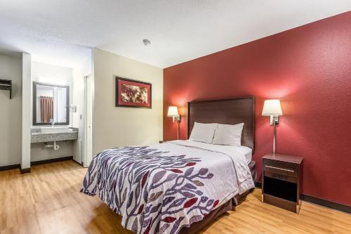 a hotel room with a bed and a red wall at Red Roof Inn Scottsburg in Scottsburg