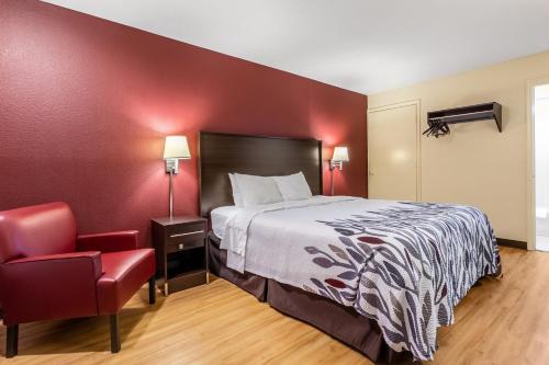 a hotel room with a bed and a red wall at Red Roof Inn Scottsburg in Scottsburg