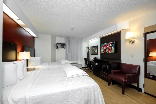 a hotel room with a large white bed and a chair at Red Roof Inn PLUS+ Palm Coast in Palm Coast