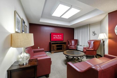 a living room with red chairs and a tv at Red Roof Inn PLUS+ Palm Coast in Palm Coast