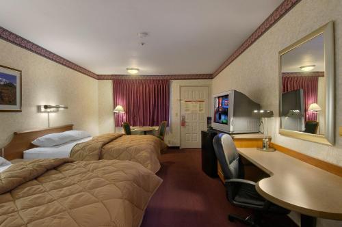 a hotel room with two beds and a television at Mariposa Inn in Victorville