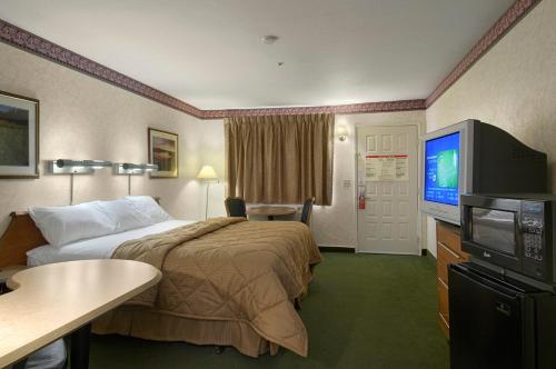 a hotel room with a bed and a flat screen tv at Mariposa Inn in Victorville