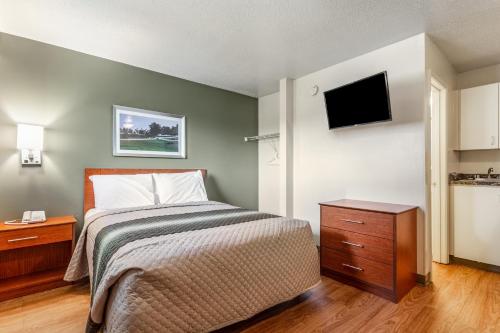 a bedroom with a bed and a flat screen tv at HomeTowne Studios by Red Roof Louisville in Louisville