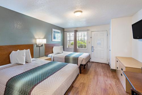 a hotel room with two beds and a flat screen tv at HomeTowne Studios by Red Roof Atlanta – Lawrenceville in Lawrenceville