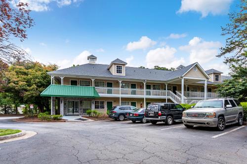 a large house with cars parked in a parking lot at HomeTowne Studios by Red Roof Atlanta – Lawrenceville in Lawrenceville