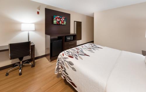 a hotel room with a bed and a desk and a television at Red Roof Inn Fort Wayne in Fort Wayne