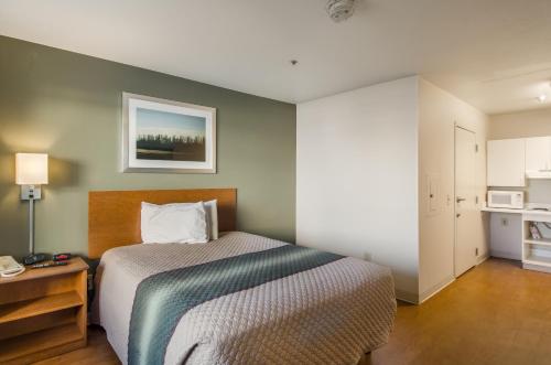 a bedroom with a bed and a table and a kitchen at HomeTowne Studios by Red Roof Denver - Airport/Aurora in Aurora