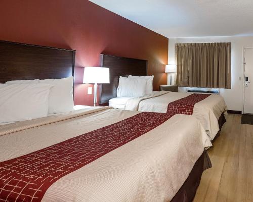 two beds in a hotel room with red walls at Red Roof Inn Dayton Huber Heights in Dayton